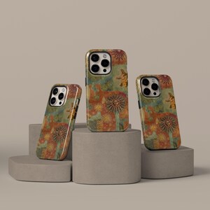 May include: Three phone cases with a colorful, abstract design featuring orange, yellow, and green hues. The cases are displayed on gray geometric pedestals, showcasing the phone's camera and button placements. The cases have a glossy finish.