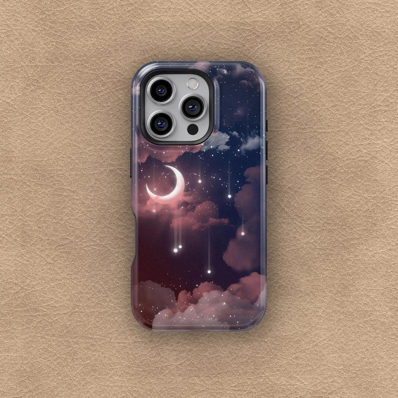 Puede incluir: Funda de tel&eacute;fono con un dise&ntilde;o de cielo nocturno con una luna creciente, estrellas y nubes en tonos rosa, morado y azul. La funda tiene un borde transparente y un recorte para la c&aacute;mara.