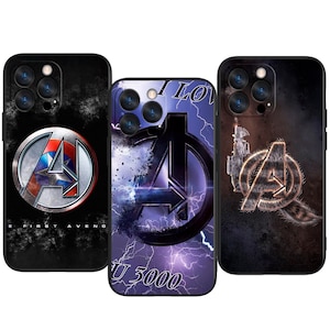 Op de afbeelding: Drie zwarte telefoonhoesjes met Avengers-logo's. Eén hoesje heeft een zilver en rood logo met de tekst "THE FIRST AVENGER". Een andere heeft een paarse bliksemachtergrond met de tekst "I LOVE U 3000". De derde heeft een gouden logo.