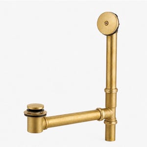 May include: A brushed brass bathtub drain and overflow assembly featuring a vertical pipe with a circular overflow plate at the top, a horizontal pipe, and a cylindrical drain stopper with black rubber gaskets at the base of the plumbing unit.