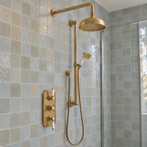 May include: A brass shower system featuring a large circular overhead shower head, a handheld shower wand with a white handle, and a rectangular wall-mounted control panel with three white lever handles, all mounted on a light blue tiled wall.