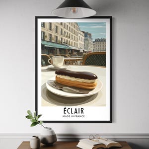 May include: Framed art print depicting a Parisian cafe. An éclair with chocolate and cream filling rests on a white plate. A cup of coffee is also visible. The print includes the text "ÉCLAIR MADE IN FRANCE".