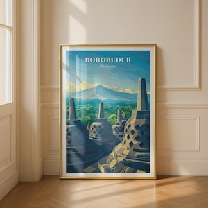 Op de afbeelding: Een ingelijste verticale kunstdruk met een gestileerde illustratie van de Borobudur-tempel in Indonesië. De afbeelding toont klokvormige stoepa's op de voorgrond met een bergketen en een blauwe lucht op de achtergrond. De tekst luidt BOROBUDUR Indonesia.