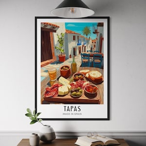 May include: A framed print featuring a Spanish tapas scene. The artwork depicts a table laden with food and drinks, including cheese, olives, and bread. The word "TAPAS" is displayed below the image, with "MADE IN SPAIN" underneath.