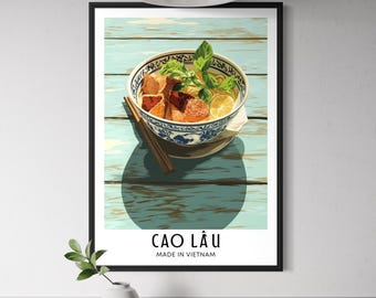 May include: Framed art print featuring a bowl of Cao Lầu, a Vietnamese noodle dish, with chopsticks. The bowl is set on a light blue wooden surface. The text "CAO LÂU MADE IN VIETNAM" is displayed below the image.