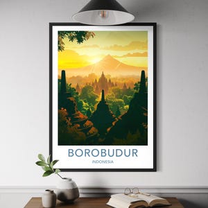 May include: A framed art print depicting Borobudur, Indonesia, at sunset. The image shows the temple complex set against a backdrop of mountains and a golden sky. The text "BOROBUDUR INDONESIA" is displayed at the bottom of the print.