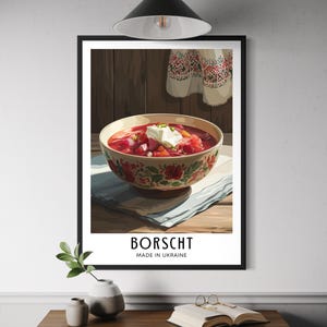 Peut inclure: Une affiche encadrée représentant un bol de bortsch, une soupe ukrainienne traditionnelle, garnie de crème. Le bol est orné de motifs floraux. Les mots "Borscht" et "Made in Ukraine" sont imprimés en dessous.
