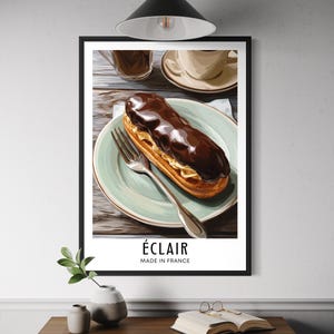 May include: A framed print showing an éclair on a plate with a fork, and coffee cups. The éclair is covered in dark chocolate. The text "ÉCLAIR MADE IN FRANCE" is displayed at the bottom of the print.