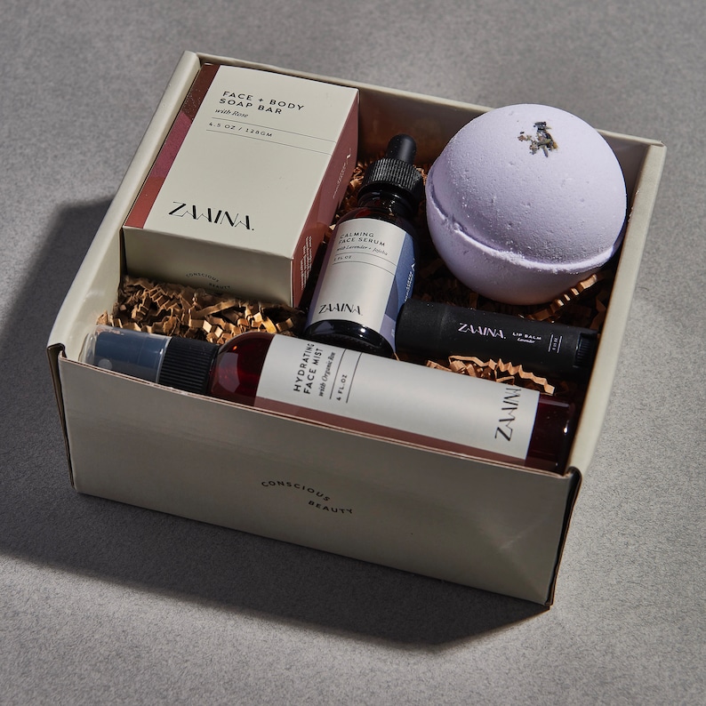 Peut inclure: Une bo&icirc;te-cadeau remplie de produits de beaut&eacute;, dont un savon pour le visage et le corps, un s&eacute;rum pour le visage, une brume pour le visage, un baume &agrave; l&egrave;vres et une bombe de bain. La bo&icirc;te est blanche avec les mots "Conscious Beauty" imprim&eacute;s en bas. Tous les produits sont de la marque "ZAWINA."