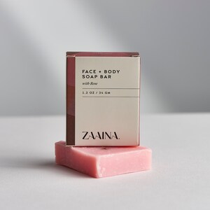 K&ouml;nnte beinhalten: Eine rosa Seifenstange mit dem Text "FACE + BODY SOAP BAR with Rose 1.2 OZ / 34 GM ZAMINA." auf der Verpackung.