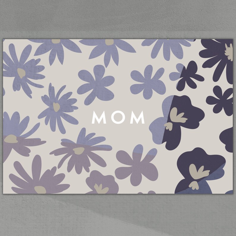Peut inclure: Une carte de couleur gris clair avec un motif floral dans des tons de violet et de gris. Le mot "MOM" est imprim&eacute; en blanc au centre de la carte.