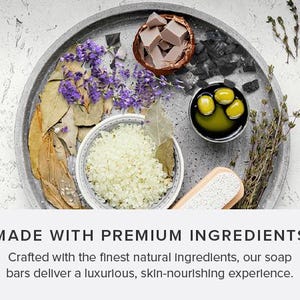 Puede incluir: Primer plano de una bandeja gris con varios ingredientes naturales, incluyendo lavanda, hojas de laurel, sal marina, aceite de oliva y carb&oacute;n. Los ingredientes est&aacute;n dispuestos de forma visualmente atractiva, lo que sugiere un producto de spa o belleza.