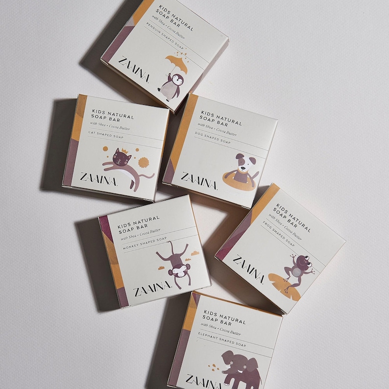 May include: Six square boxes of Zaaina Kids Natural Soap Bar with Shea and Cocoa Butter. Each box features a unique animal illustration including a penguin, cat, dog, monkey, frog, and elephant, with text identifying the specific animal-shaped soap.