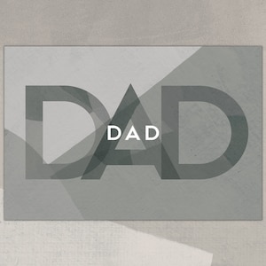 Op de afbeelding: Een grijze en witte kaart met het woord "DAD" in grote, vetgedrukte, zwarte letters. De letters zijn gelegd over een geometrisch patroon van grijze driehoeken.