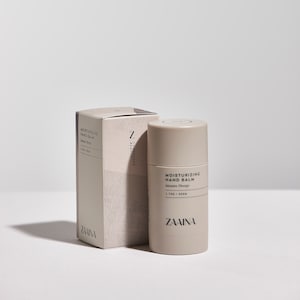 May include: A beige and white tube of hand balm with the text "Moisturizing Hand Balm" and "Intensive Therapy" on the front. The tube is labeled "Z Conscious Beauty" and "ZAAINA".