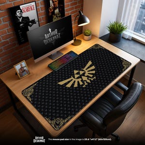 May include: Black desk mat with a gold emblem and diamond pattern. The mat is rectangular and covers a wooden desk. The text "ARTHUR DESKMAT" is visible. The mouse pad size is 60cm x 120cm.
