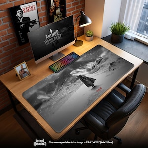 Puede incluir: Alfombrilla de escritorio en blanco y negro con una ilustración dramática de una figura con capa sobre un fondo montañoso. La alfombrilla mide 60 cm x 120 cm y tiene el texto "ARTHUR DESKMAT".