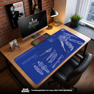 Puede incluir: Una alfombrilla de escritorio azul con un diseño de plano de un robot Gundam y armas, con el texto "UNICORN GUNDAM WEAPONS". La alfombrilla es rectangular, mide 60cm x 120cm. Una computadora, un teclado y una lámpara de escritorio están sobre el escritorio de madera.