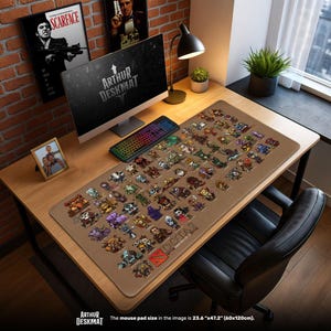 Puede incluir: Una alfombrilla de escritorio rectangular grande con un fondo marrón que presenta numerosas ilustraciones coloridas de personajes de Dota 2. La alfombrilla, que mide 60cm x 120cm, tiene el texto "ARTHUR DESKMAT" y "DOTA2" impreso. El escritorio es de madera.