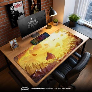 May include: A large desk mat with a vibrant, yellow and orange landscape design. The mat, measuring 23.6" x 47.2", features the text "ARTHUR DESKMAT" and is placed on a wooden desk with a computer, keyboard, and other accessories.