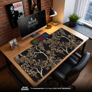 May include: A black desk mat with a gold tree branch design, a computer, and a keyboard. The desk mat is 60cm x 120cm. The text "ARTHUR DESKMAT" is visible. The background includes a desk, chair, and framed artwork.
