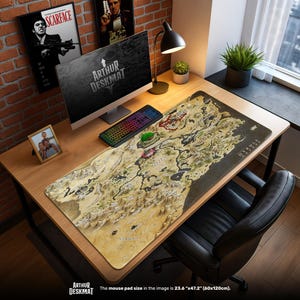 May include: A rectangular desk mat with a map design, the text "HYRULE" and "ARTHUR DESKMAT". The mat is 60cm x 120cm. A computer, keyboard, and other desk accessories are on the wooden desk. The desk is next to a window.