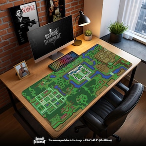 May include: A large desk mat with a pixelated map design in shades of green, brown, and blue. The mat, measuring 60cm x 120cm, features the text "ARTHUR DESKMAT" at the bottom. A computer, keyboard, and other desk accessories are on the desk.