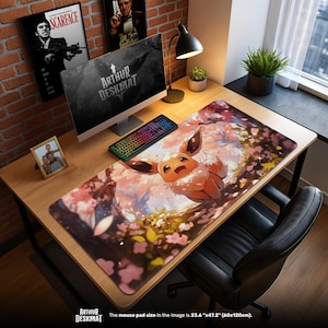 Könnte beinhalten: Eine große Schreibtischunterlage mit einer Illustration eines Eevee-Charakters in einer Kirschblütenlandschaft. Die Matte misst 60 cm x 120 cm. Der Text "ARTHUR DESKMAT" ist sichtbar. Ein Computer, eine Tastatur und anderes Schreibtischzubehör befinden sich auf dem Schreibtisch.