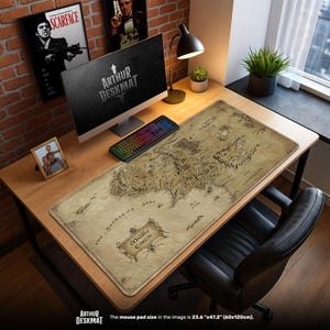 May include: A large rectangular desk mat with a map design, featuring the text "Middle Earth" and "The Sundering Seas". The mat is beige with a detailed map illustration. The size is 23.6" x 47.2".