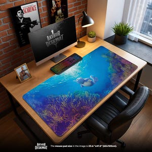 May include: A large desk mat with an underwater scene featuring a dolphin swimming above coral. The mat is 23.6" x 47.2" and has the text "ARTHUR DESKMAT" at the bottom. A computer, keyboard, and other desk accessories are visible.