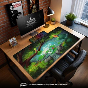 May include: A large desk mat with a colourful illustration of a stream scene with a frog. The mat, measuring 60cm x 120cm, features the text "ARTHUR DESKMAT". A computer, keyboard, and other desk accessories are visible on the wooden desk.