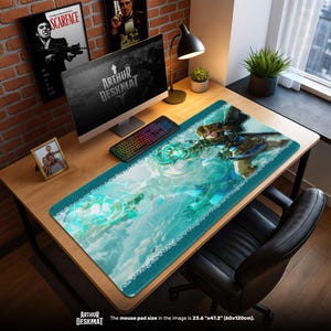 Peut inclure: Tapis de bureau rectangulaire avec un personnage fantastique dans des tons de bleu et de turquoise. Le tapis a une bordure turquoise et un bord décoratif blanc. Le texte "ARTHUR DESKMAT" est visible. Dimensions : 60cm x 120cm.