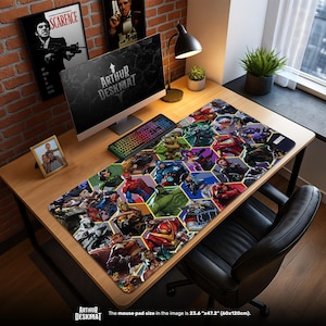 May include: A large rectangular desk mat featuring a colorful collage of Marvel comic book characters in a hexagonal pattern. The mat is 23.6" x 47.2" (60x120cm) and has the text "ARTHUR DESKMAT" at the bottom.