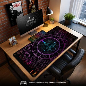 Può includere: Tappetino da scrivania nero con un design geometrico raffigurante un triangolo con un occhio, circondato da un cerchio e una scritta. Il tappetino, che misura 60cm x 120cm, ha il testo "ARTHUR DESKMAT". Un computer, una tastiera e una lampada da scrivania sono sulla scrivania di legno.