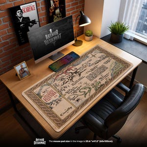 Puede incluir: Una alfombrilla de escritorio rectangular con un diseño de mapa, con un fondo beige e ilustraciones detalladas en negro, verde y rojo. La alfombrilla tiene el texto "ARTHUR DESKMAT" en la parte inferior. La alfombrilla mide 60cm x 120cm.