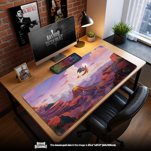 May include: A large rectangular desk mat with a colorful landscape design featuring a dragon. The mat is 23.6" x 47.2" and has the text "ARTHUR DESKMAT" at the bottom. The image also shows a computer setup.