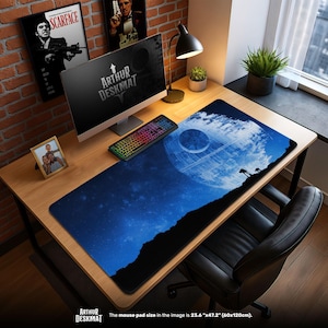 May include: A desk setup featuring a large mouse pad with a blue space scene and a Death Star design. The pad is 23.6" x 47.2". The desk also has a keyboard, monitor, and framed photos. The words "ARTHUR DESKMAT" are visible.