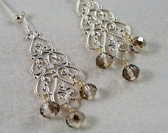 May include: A pair of silver filigree earrings with dangling brown crystal beads.