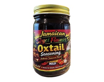 May include: A jar of Jamaican Spyci Flava's Oxtail Seasoning with a gold lid. The label features text and images of ingredients like peppers and garlic. The seasoning is labeled as "Mild" and "Authentic Jamaican Flavor!"