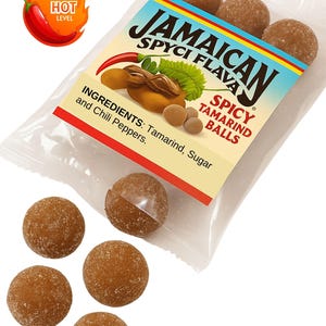 Könnte beinhalten: Eine transparente Verpackung mit mehreren braunen, kugelförmigen Jamaican Spyci Flava Spicy Tamarind Balls. Die Verpackung zeigt Text und Illustrationen, darunter eine Chili-Pfeffer-Grafik, die einen "Hot Level" anzeigt. Zutaten: Tamarinde, Zucker und Chili-Pfeffer.