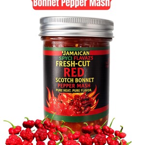 May include: A jar of Jamaican Authentic Red Scotch Bonnet Pepper Mash with a silver lid. The label reads "FRESH-CUT RED SCOTCH BONNET PEPPER MASH". Red Scotch Bonnet peppers are scattered in front of the jar.
