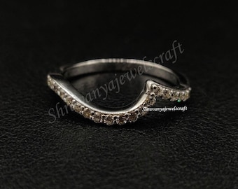 May include: A silver-toned curved wedding band featuring a row of small, clear, round-cut stones set along the top edge. The ring has a distinct wave-like contour designed to fit against another ring, with the text Shravanyajewelcraft visible.