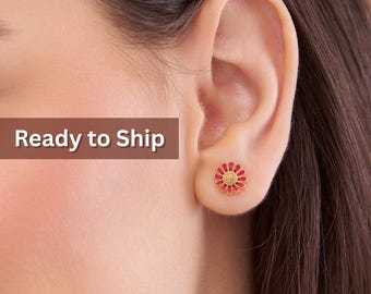 May include: A close-up of a person's ear with a gold stud earring. The earring is a small, red and gold flower design. The text "Ready to Ship" is in a brown rectangle in the upper left corner.