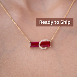 May include: A gold necklace with a rectangular, deep red gemstone and a half-circle of small, clear stones. The necklace is centered on a person's chest. The text "Ready to Ship" is in a brown rectangle.