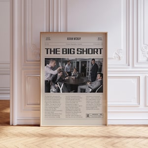 May include: A framed movie poster for "The Big Short" in a newspaper style. The poster features a group of men in suits around a table, with text including the movie title, director Adam McKay, and a movie report. The poster is in a wooden frame.