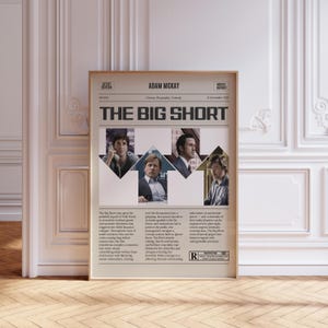 May include: A framed movie poster for "The Big Short" featuring Adam McKay. The poster has a newspaper design with images of the actors. The text includes the movie title, director's name, and a rating.