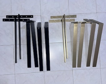 May include: A set of eight metal furniture legs, including four matte black legs and four metallic gold legs. Each leg features a flat, T-shaped mounting plate at the top with pre-drilled holes for attachment, extending into a straight, vertical bar.