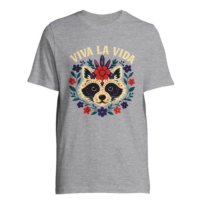 May include: A gray t-shirt featuring a raccoon design with floral accents and the text "VIVA LA VIDA" in yellow. The raccoon has a decorative face with a floral crown, surrounded by red, blue, and purple flowers.
