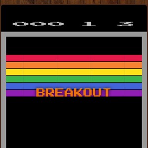 Puede incluir: Una pantalla de tel&eacute;fono m&oacute;vil muestra una interfaz de videojuego retro. El juego es "Breakout", con una fila superior de bloques de colores del arco&iacute;ris. La pantalla muestra el t&iacute;tulo del juego y un bot&oacute;n para comenzar.