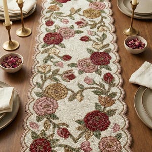 Può includere: Runner da tavolo con perline con un motivo floreale a rose nei toni del rosso, rosa e oro. Il runner ha un bordo smerlato ed è posto su un tavolo di legno. Sono presenti anche candele e piatti.